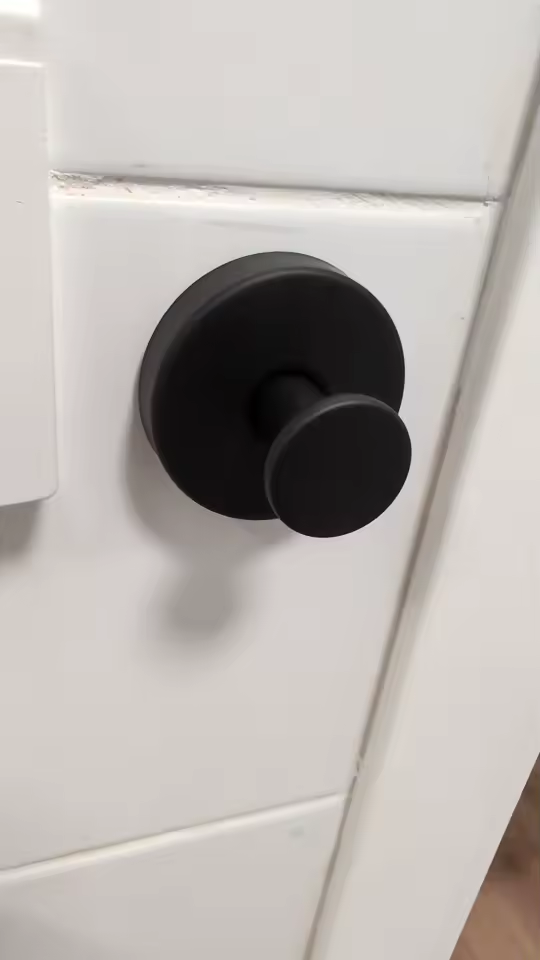 Matte black suction hook on white bathroom tiles