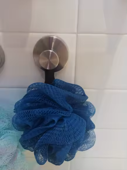 Brushed silver suction hook holding a blue shower puff