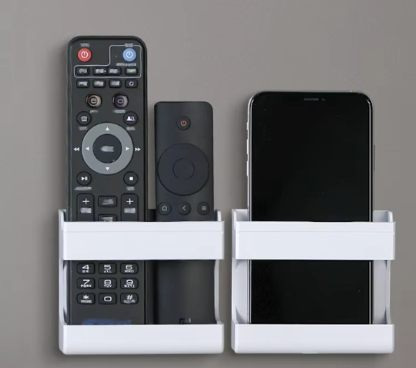 Two white wall organisers holding remotes and a phone
